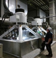 An industrial setting showing a large centrifuge unit with a worker standing next to it